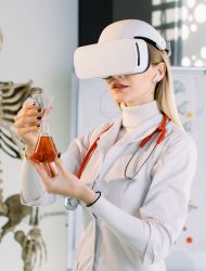 Female scientist, bio chemist or doctor using futuristic VR goggles headset and holding glass flask with new red substance for analisys. Biotechnology, medicine, chemistry concept.